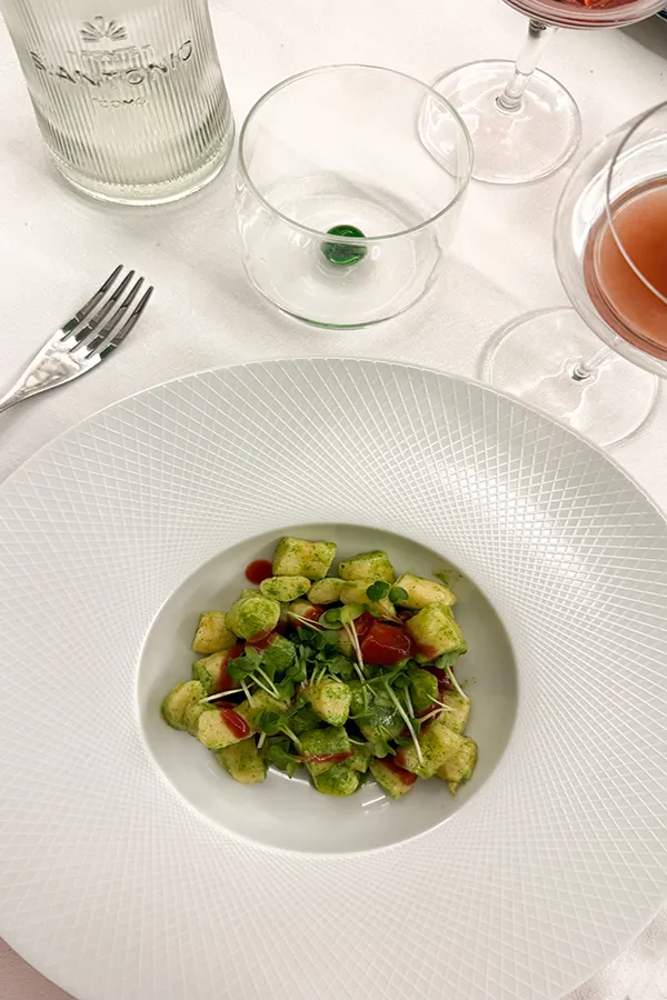 gnocchetti piatto di gnocchetti con rucola su toaglia bianca e bicchieri di vino